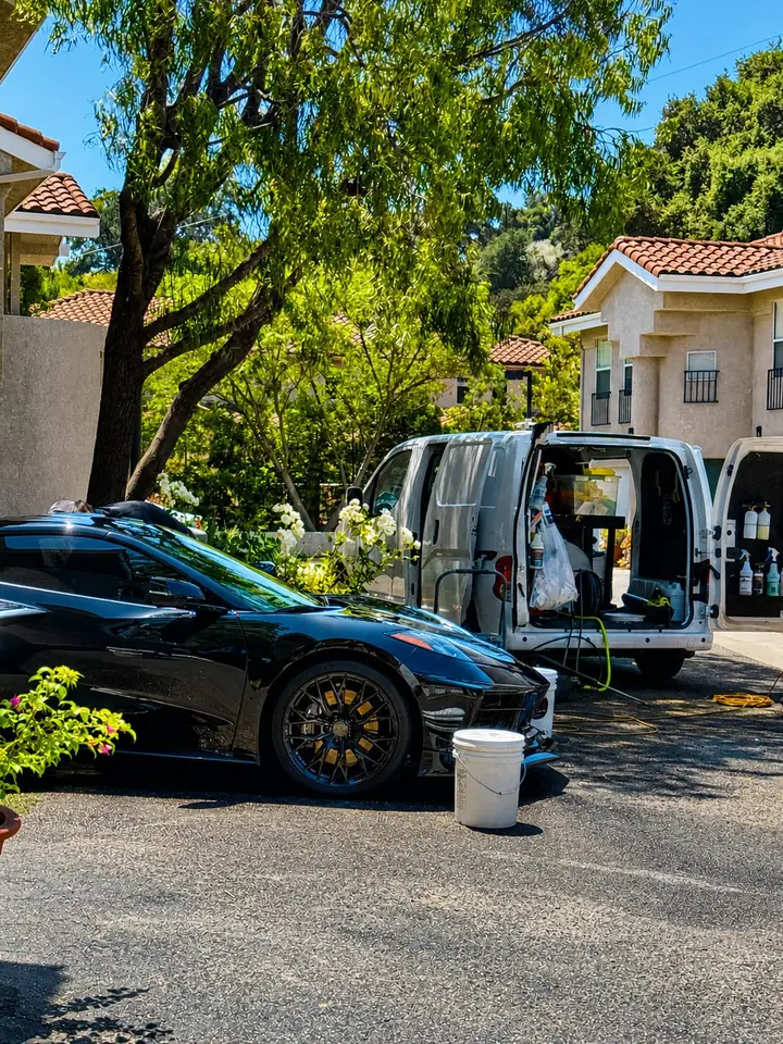 Black sports car finished in a driveway with the SS Detail mobile van behind it