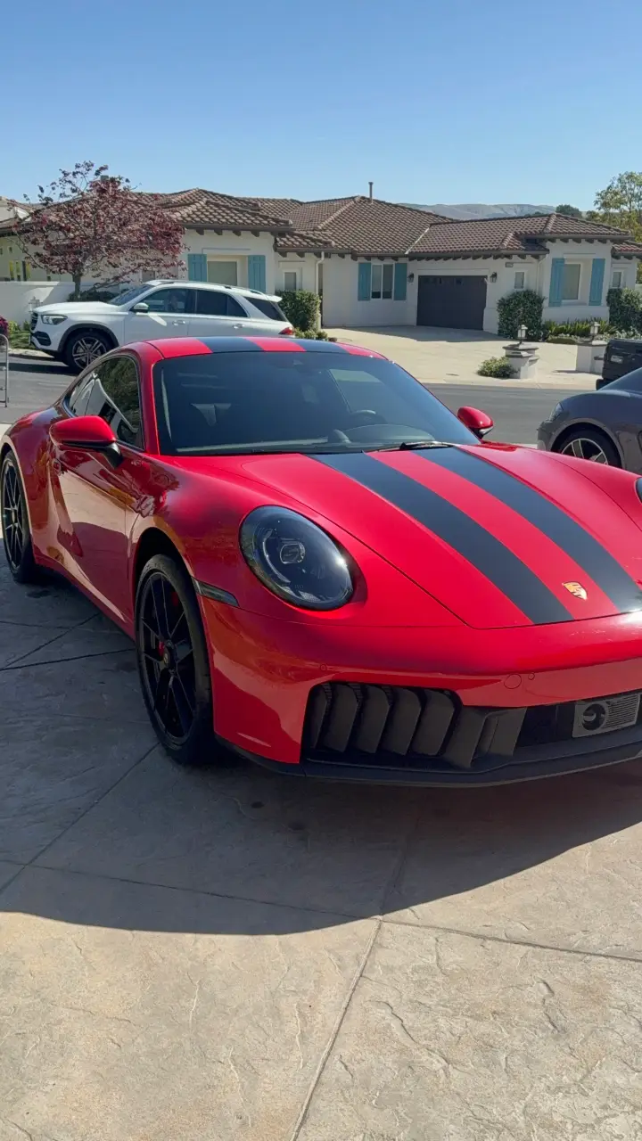 Red Porsche 911 with black stripes, freshly detailed in a driveway