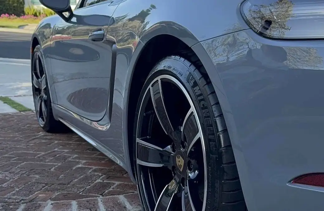 Rear quarter of a grey Porsche 718 with sealed, glossy paint and a dressed tire